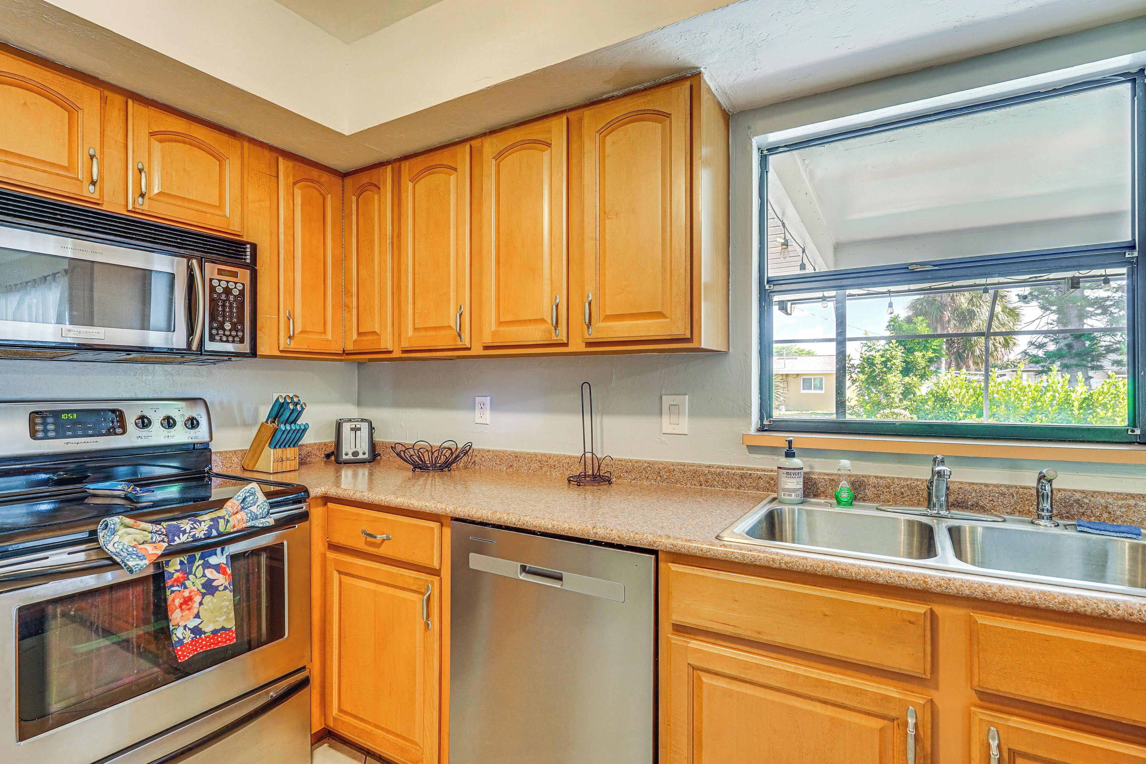 A kitchen with wooden cabinets, a stainless steel microwave, an oven, and a dishwasher.