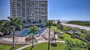 A high-rise hotel with a pool area, palm trees, and a view of the ocean. - Sunny Getaway: Community Amenities, Walk to Beach! (Marco Island)