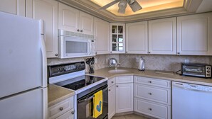 A kitchen with white cabinets, a microwave, stove, oven, dishwasher, and a ceiling fan. - Sunny Getaway: Community Amenities, Walk to Beach! (Marco Island)