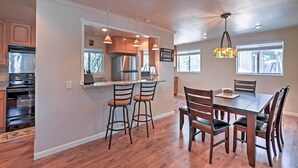 A modern kitchen with wooden cabinets, a stainless steel refrigerator, and a dining area with a wooden table and chairs.