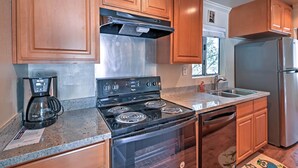 A kitchen with wooden cabinets, a stainless steel refrigerator, a built-in oven, and a coffee maker.