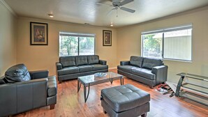 A spacious living room with leather sofas, a glass coffee table, and hardwood flooring.