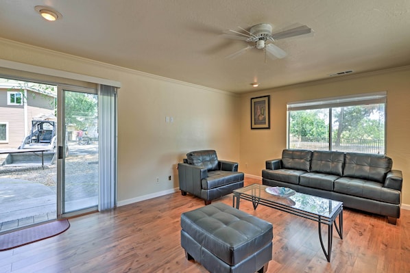 A spacious living room with a large black leather sofa, a smaller armchair, and a glass coffee table. - Remodeled & Cozy Gilroy Guest House Near Downtown! (Gilroy)