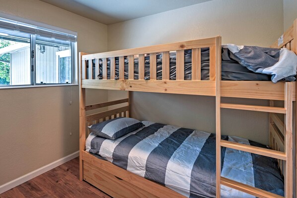 A bunk bed with a striped bedding, a window with blinds, and a wooden floor. - Remodeled & Cozy Gilroy Guest House Near Downtown! (Gilroy)
