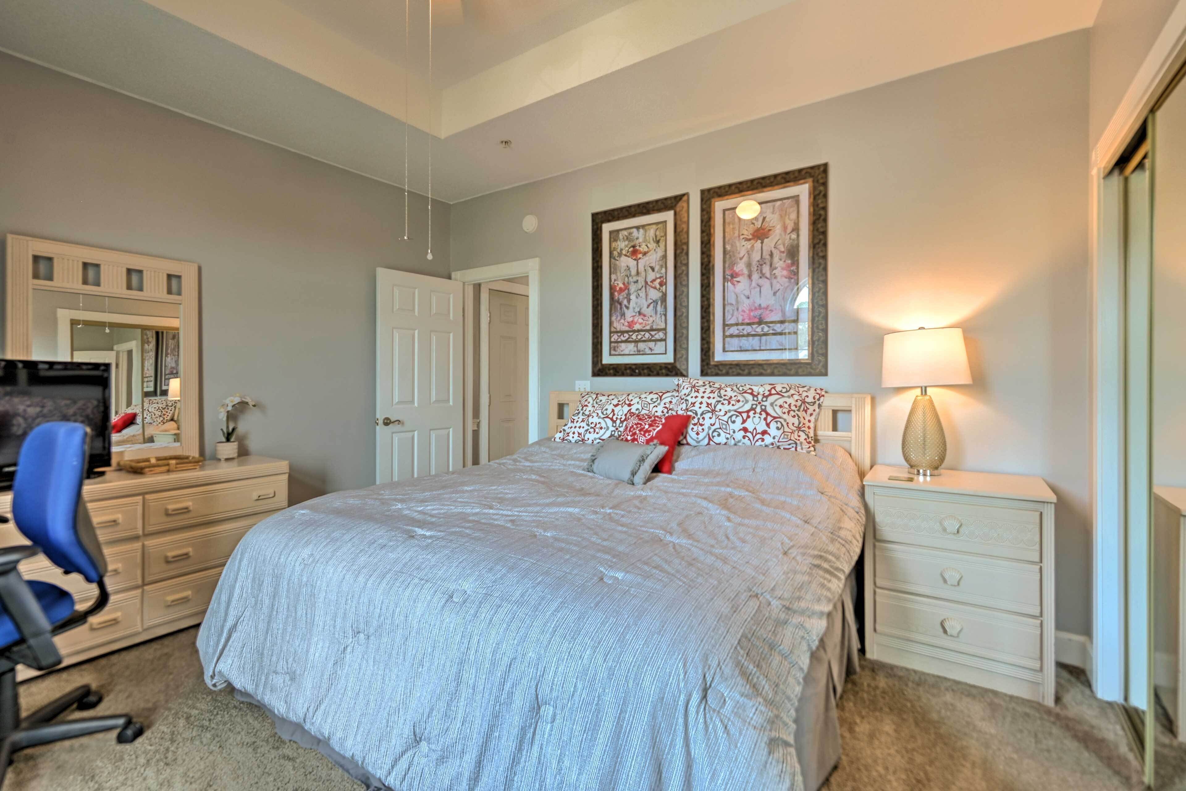 A bedroom with a bed, a desk, a chair, a dresser, and two framed pictures on the wall.