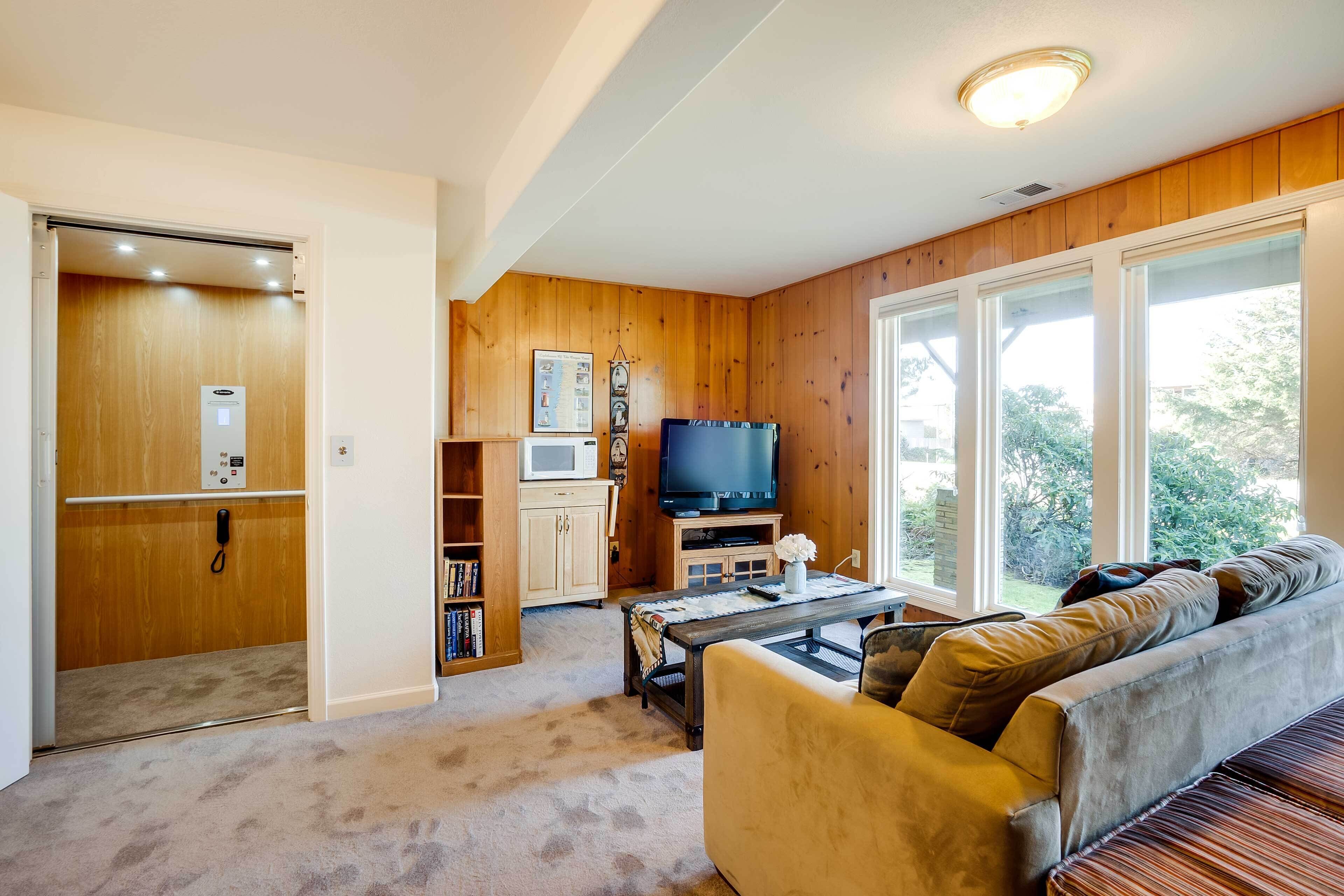 A living room with a sofa, coffee table, TV, and wooden walls.