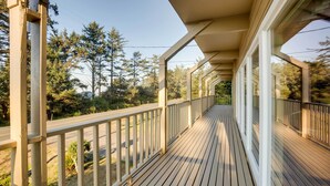 A wooden deck with railings, overlooking a road and trees. - Fishermen's Paradise in Coos Bay: Walk to Beach! (Coos Bay)