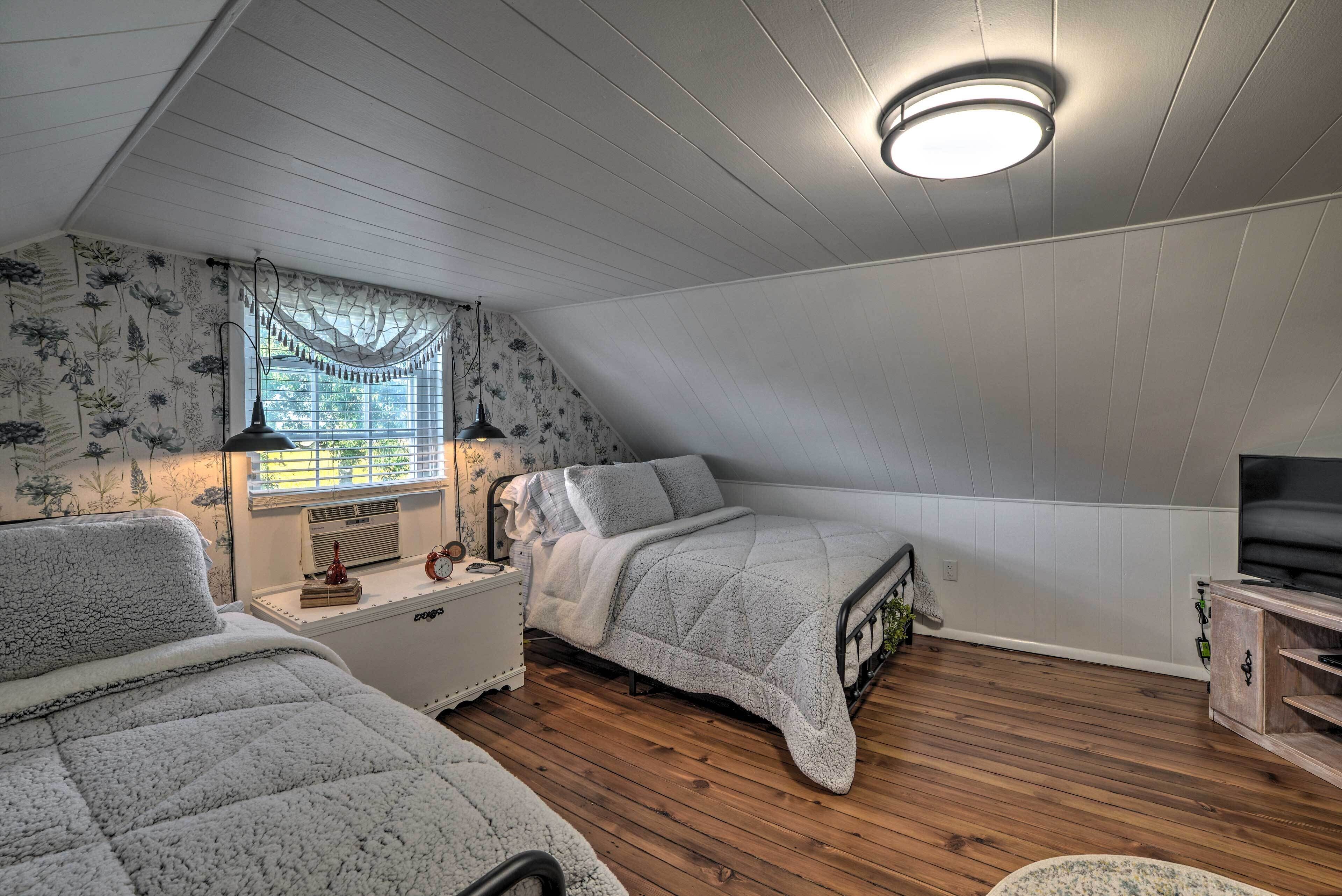 A bedroom with two beds, a TV, and a window with blinds.