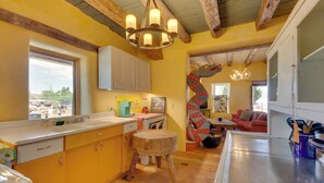 A kitchen with wooden beams, a large island, and a dining area with a red sofa. - Santa Cruz Home w/ Mountain Views! (Santa Cruz)