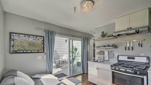 Cocina moderna con estufa, horno y cuchillos colgados. Hay un sofá con cojines y un mapa en la pared.