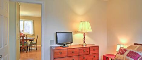 A bedroom with a bed, a dresser with drawers, a television on a stand, and a lamp.