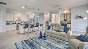 A modern kitchen with white cabinets, a central island with bar stools, and a dining area. - Private Hot Tub: Canal-front Home in Cape Coral! (Cape Coral)