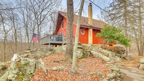 Un chalet rustique doté d’une cheminée, entouré d’arbres et bordé d’un sentier en pierre.