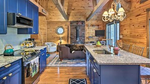 L’intérieur d’une cabane comprenant une cuisine, un coin repas et une cheminée.