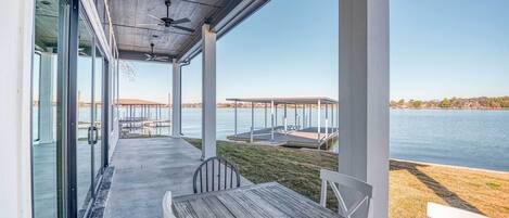 A covered outdoor area with a table and chairs, overlooking a body of water and a dock.