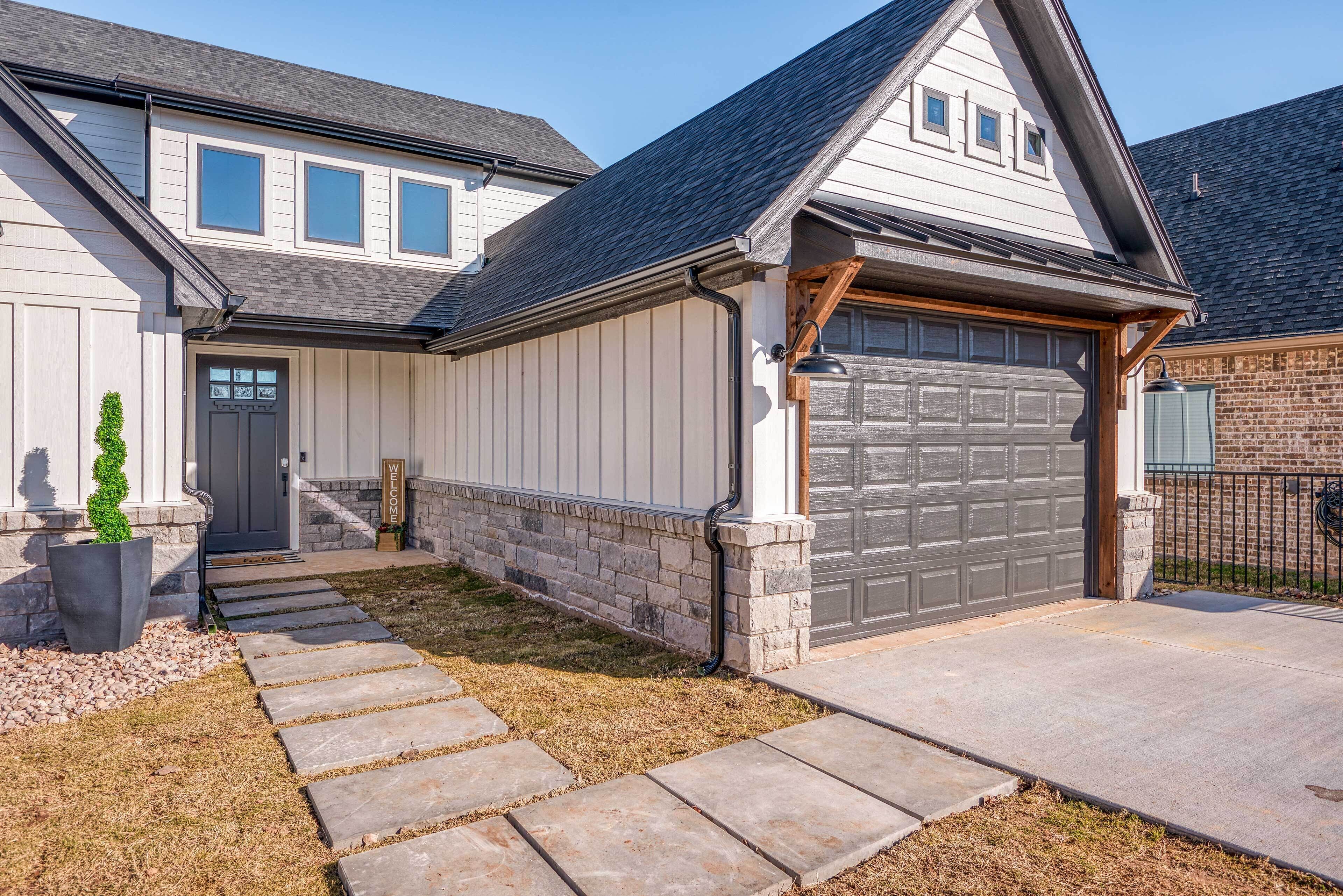 A residential house with a garage, stone pathway, and a small garden.