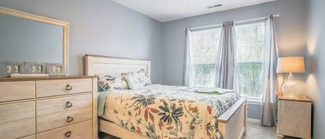 A bedroom with a bed, dresser, nightstand, and a ceiling fan.