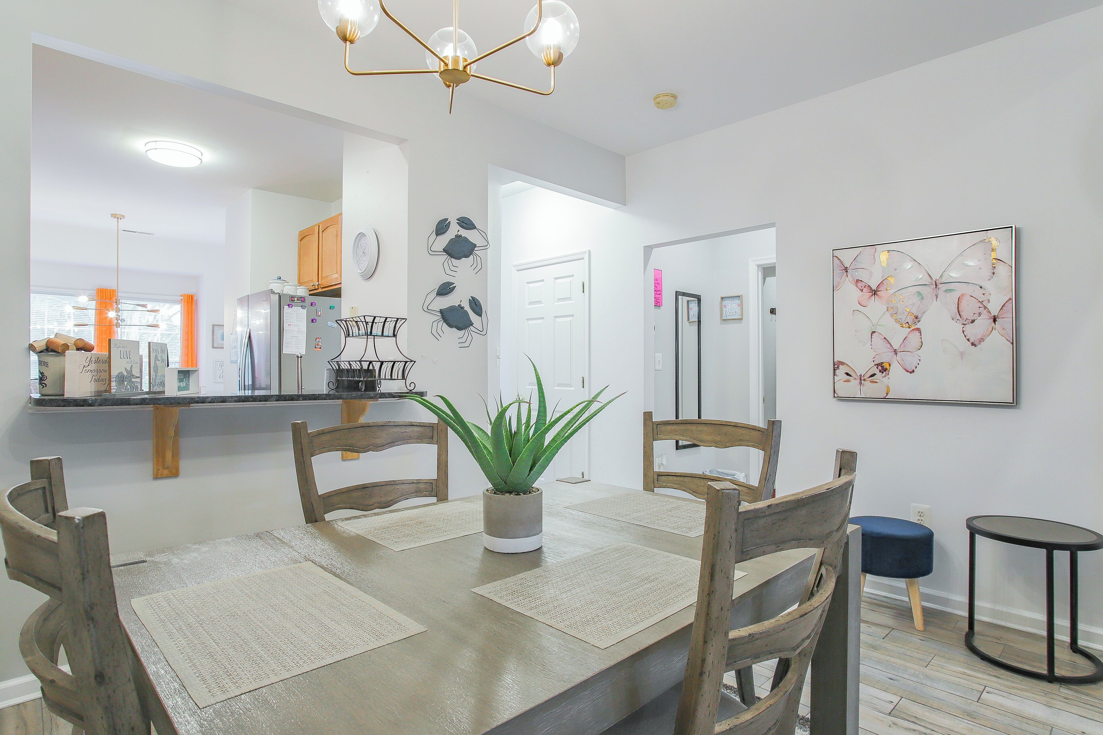 A dining area with a wooden table, chairs, a potted plant, and a chandelier.