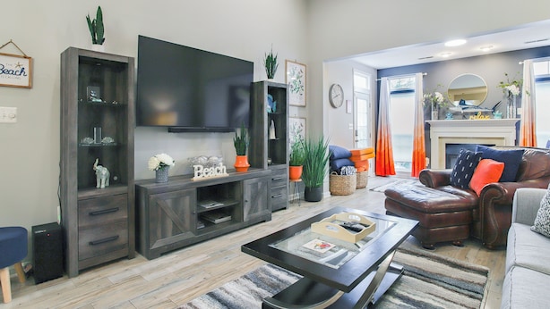 A living room with a flat-screen TV, dark wood furniture, a fireplace, and a view of the outdoors. - 3 Mi to Boardwalk: Bethany Beach House w/ Patio! (Ocean View)