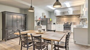 A modern kitchen with a dark wood cabinet, a wooden dining table, and four chairs. There are overhead lights and a stainless steel range hood. - Himrod Vacation Rental 3 Mi to Seneca Lake! (Himrod)