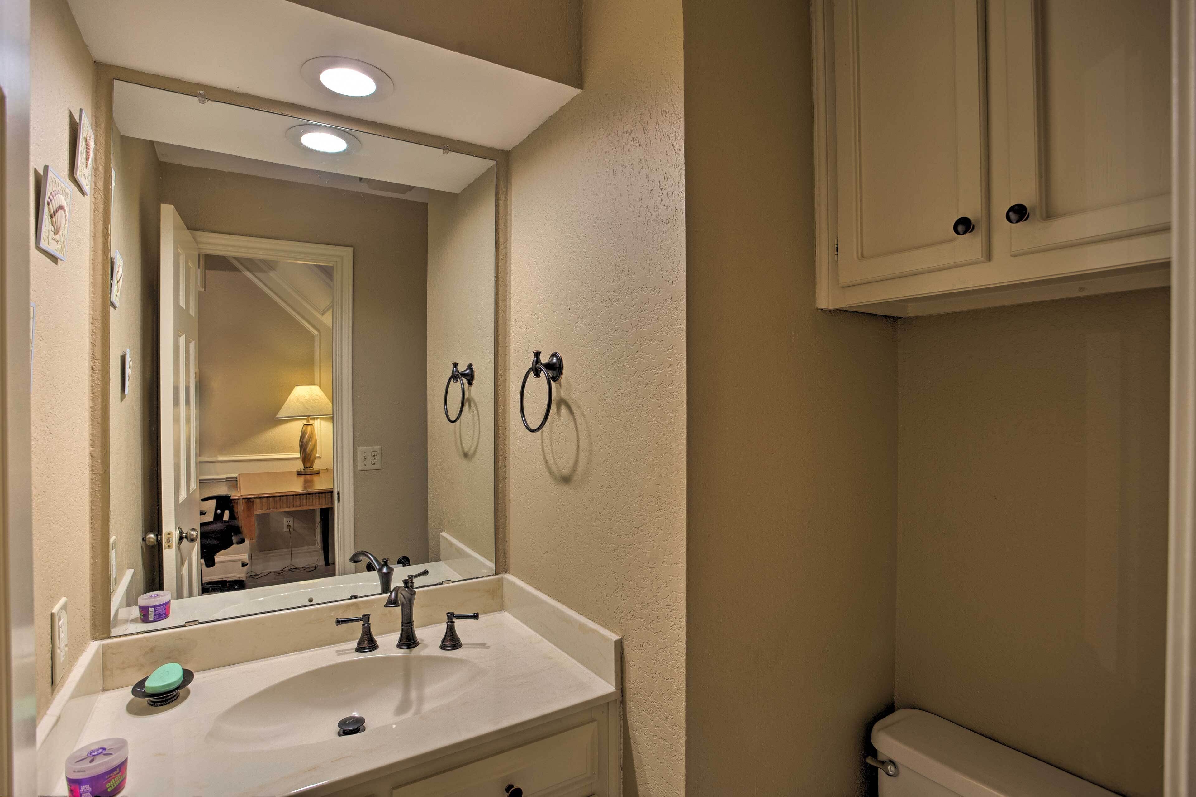 A bathroom with a white sink, mirror, and cabinets.