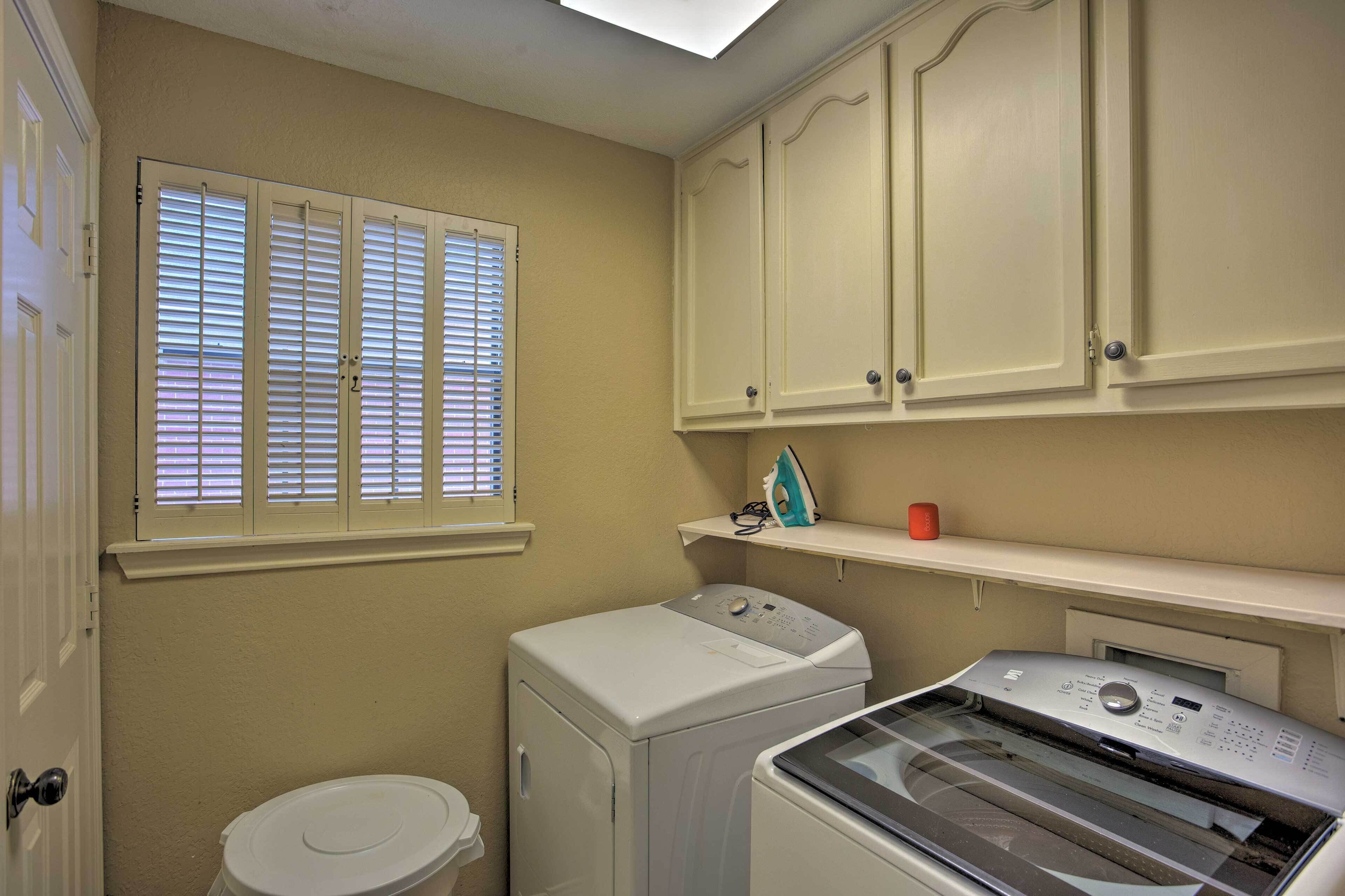 A laundry room with a washing machine, dryer, and ironing station.