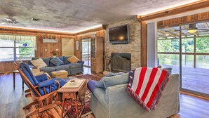 A spacious living room with a fireplace, comfortable seating, and large windows offering a view of the outdoors. - Charming Abode w/ Dock on the Suwannee River (Bell)