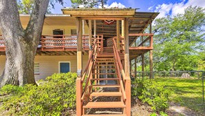 A wooden staircase leading to a covered porch with a view of a house and surrounding greenery. - Charming Abode w/ Dock on the Suwannee River (Bell)