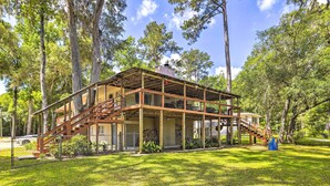 A two-story wooden cabin with a covered porch and a staircase leading to the upper level. - Charming Abode w/ Dock on the Suwannee River (Bell)