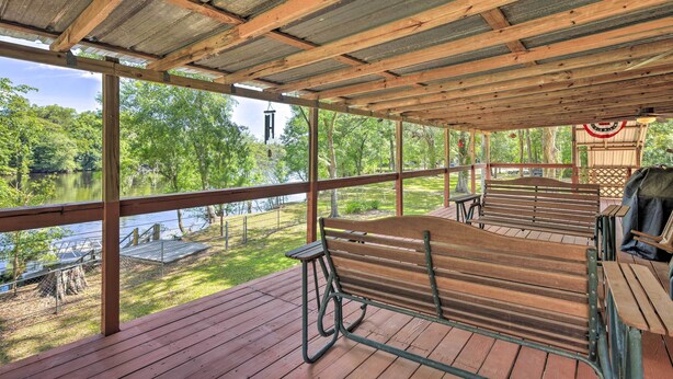 A covered outdoor area with wooden benches and a view of a lake. - Charming Abode w/ Dock on the Suwannee River (Bell)