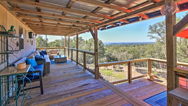 Une terrasse en bois dotée d’un espace couvert, de sièges extérieurs et offrant une vue sur le paysage.