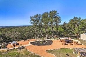 A patio area with outdoor seating, a fire pit, and a view of a forested landscape.