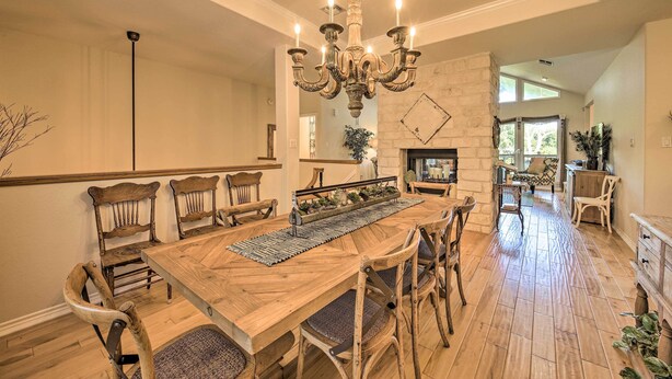 A spacious dining area with a wooden table, six chairs, and a chandelier. - Family Retreat on Guadalupe River: 2 Living Areas! (Seguin)