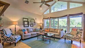 A spacious living room with a high ceiling fan, large windows, and a mix of sofas and armchairs. - Family Retreat on Guadalupe River: 2 Living Areas! (Seguin)