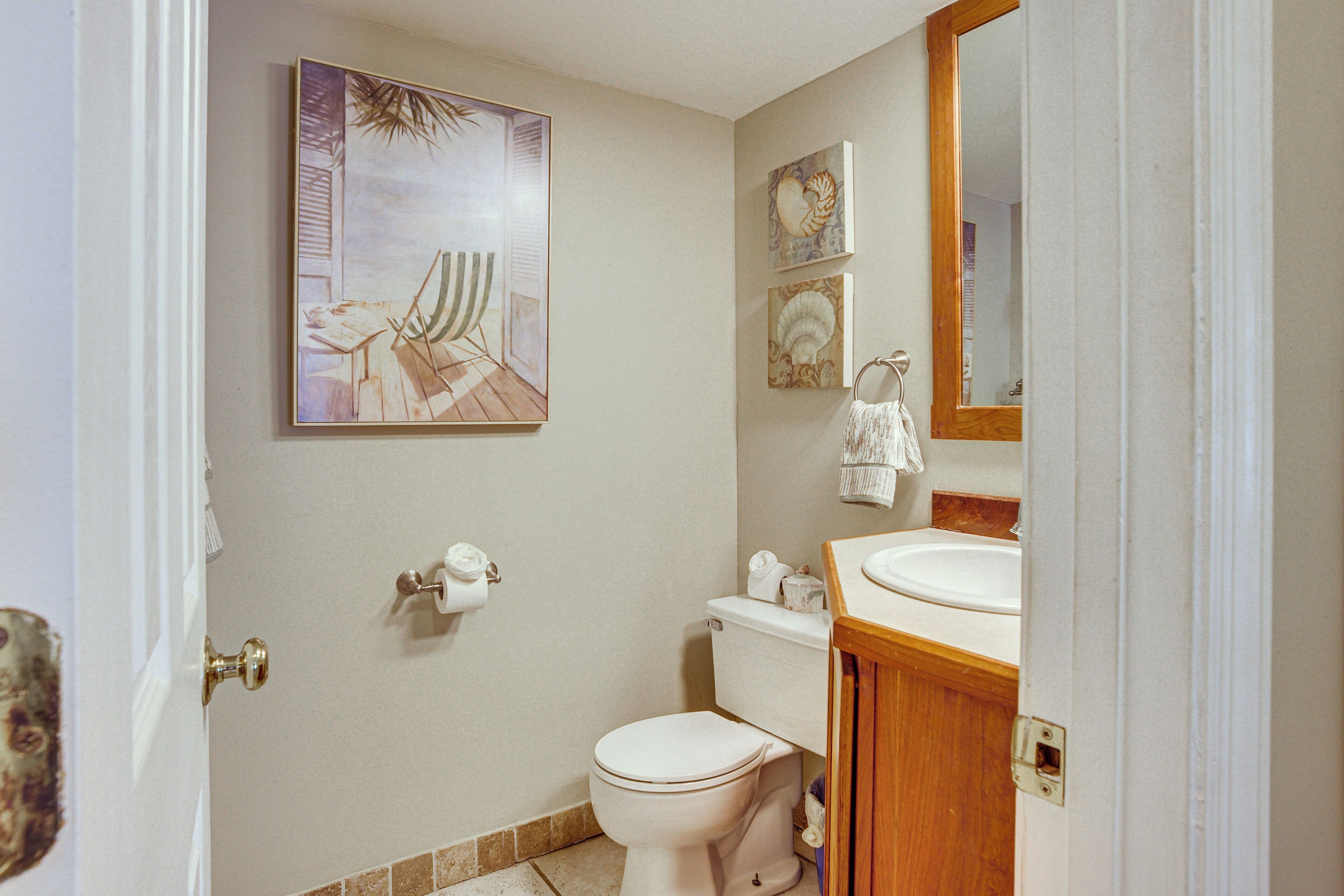 Un baño con inodoro, lavamanos y un cuadro en la pared.