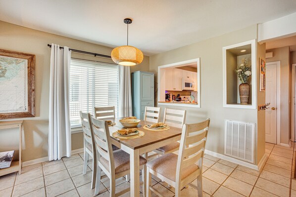 A dining area with a wooden table, chairs, and a hanging light fixture.