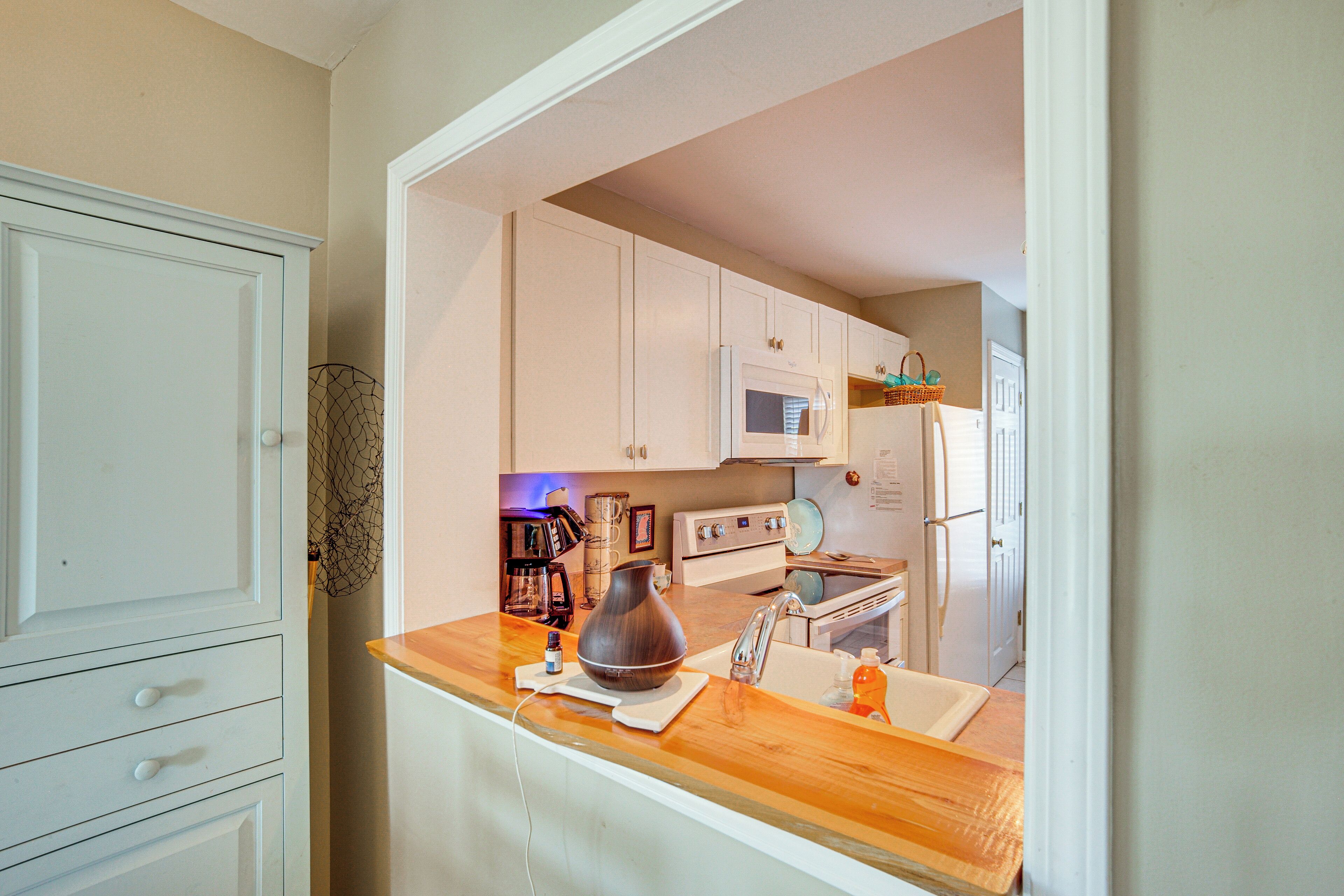 A kitchen with white cabinets, a microwave, a stove, and a wooden countertop.