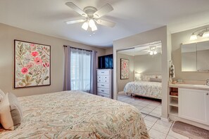 A bedroom with a bed, a ceiling fan, a dresser, a mirror, and a television. - Harbor Island Condo With Deck - Steps to Beach! (Harbor Island)