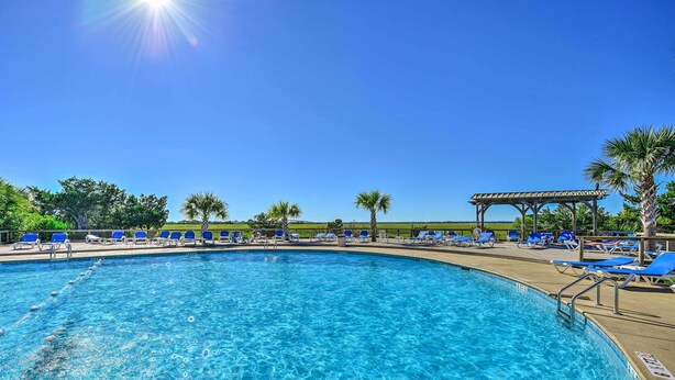 A clear blue swimming pool with blue lounge chairs and a pergola structure. - Harbor Island Condo With Deck - Steps to Beach! (Harbor Island)