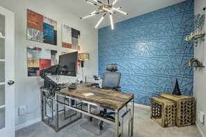 Una oficina moderna con un escritorio de madera, una computadora y una pared azul con textura.