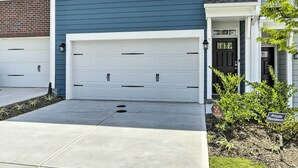 A two-story residential building with a blue exterior, white garage doors, and a black front door. - Sleek Durham Townhome Near Dtwn w/ Balcony! (Durham)