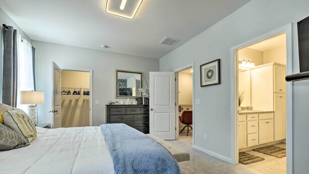 A bedroom with a bed, a dresser, a mirror, and a door leading to a bathroom. - Sleek Durham Townhome Near Dtwn w/ Balcony! (Durham)