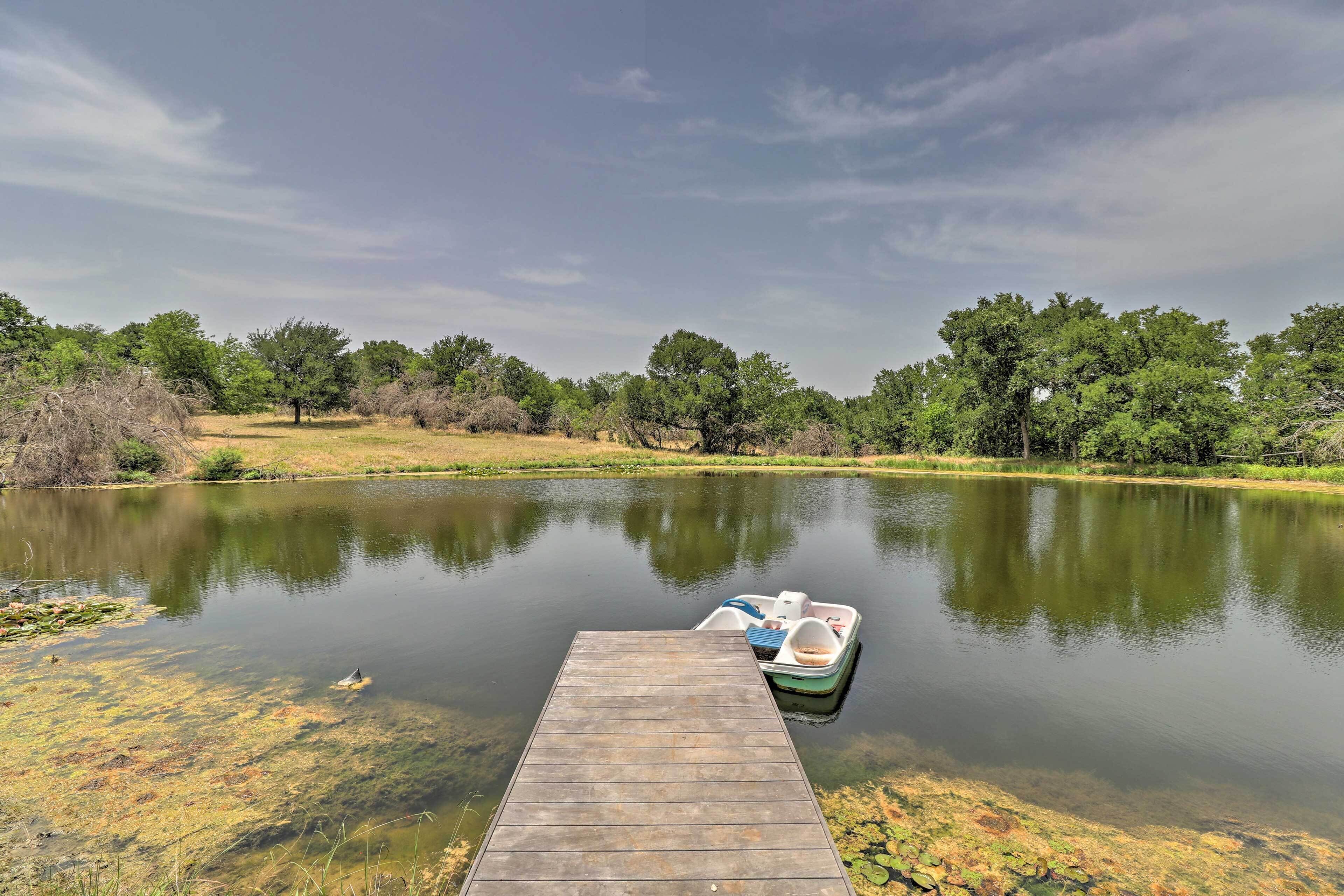 A calm lake with a wooden dock and a small boat.