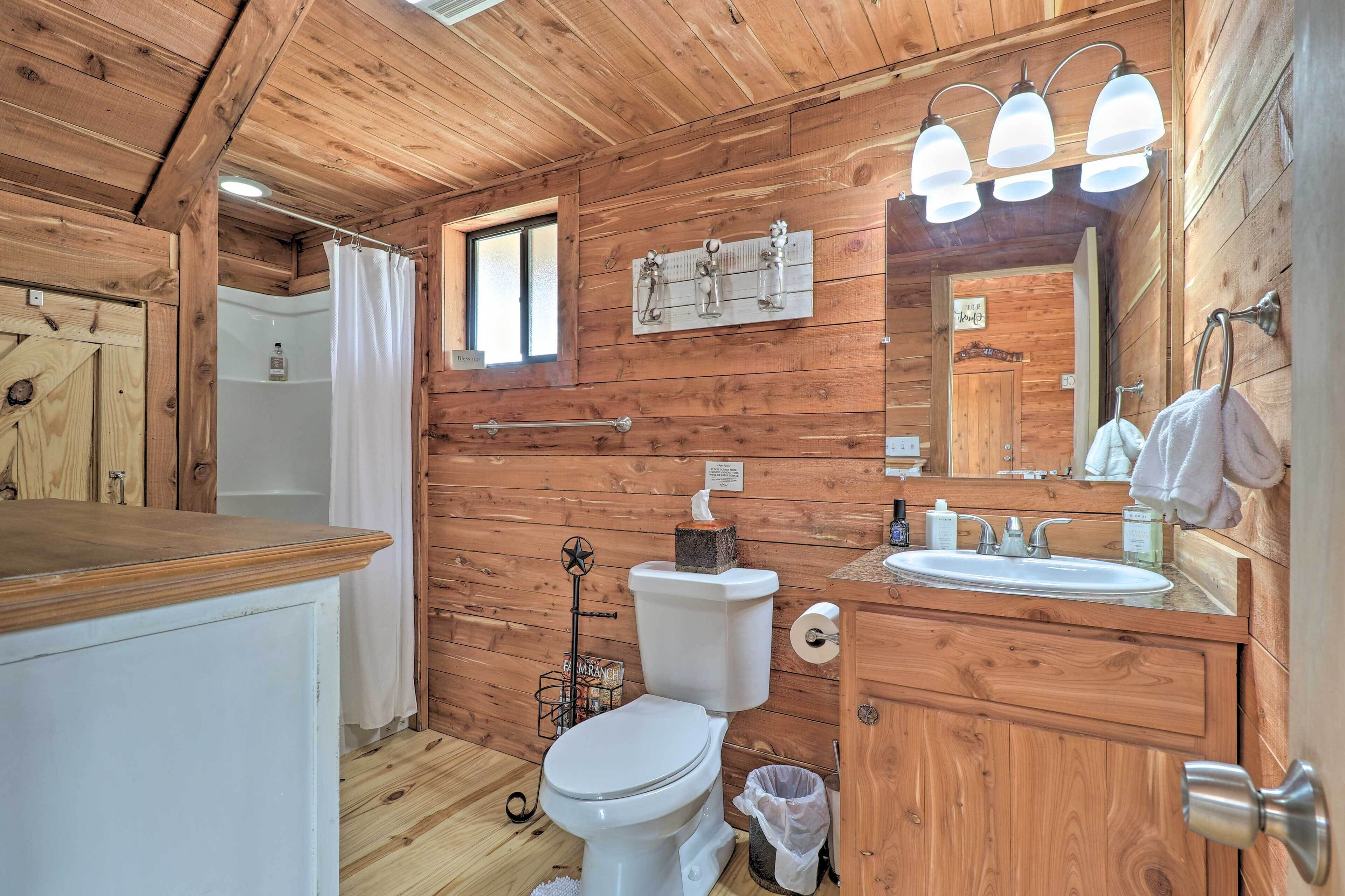 Bagno di una baita in legno, con il water, il lavandino e uno specchio.
