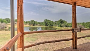 A wooden deck with a view of a pond and trees.