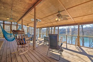 Une terrasse en bois avec une chaise berçante, un hamac et une chaise avec un dossier.