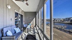 A balcony with wicker furniture, a ceiling fan, and a view of a waterfront with houses and a dock. - ~ 2 Mi to Cherry Grove Beach: Little River Condo (Little River)