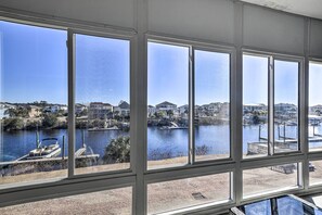 Blick durch große Fenster auf einen Fluss mit Booten, Anlegestellen und Wohnhäusern im Hintergrund.