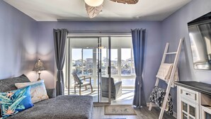 A living room with a sofa, a lamp, a view through a glass door to a balcony, and a ladder leaning against the wall. - ~ 2 Mi to Cherry Grove Beach: Little River Condo (Little River)