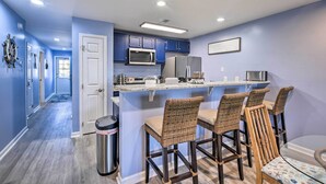 A modern kitchen with blue cabinets, a central island with bar stools, and a microwave. - ~ 2 Mi to Cherry Grove Beach: Little River Condo (Little River)